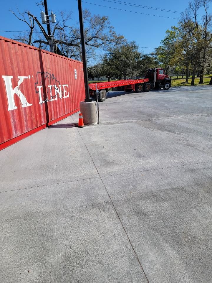 Red KLINE shipping container beside a parked red trailer in a sunny lot with trees and pavement