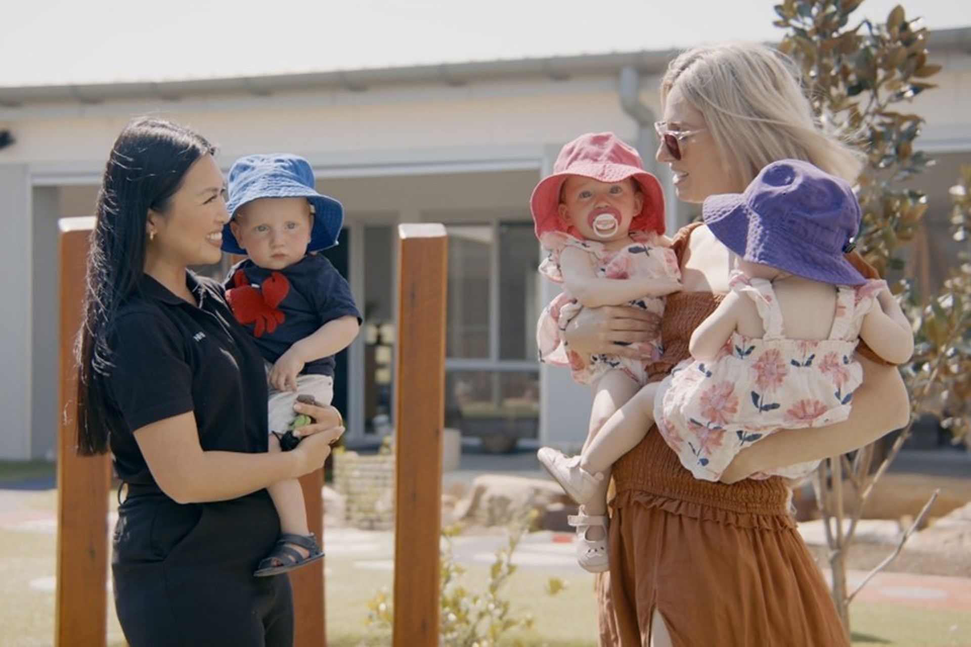 Women Holding Babies — Shell Heights, NSW — Junior Einsteins A woman is holding two babies and talking to another woman.