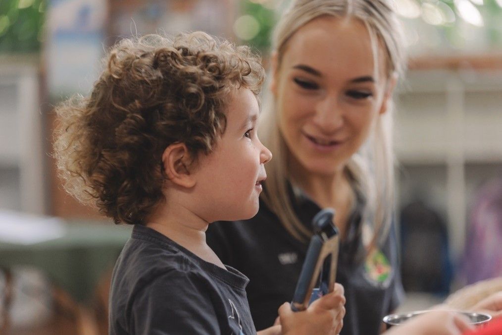 A woman is talking to a young boy who is holding a toy.