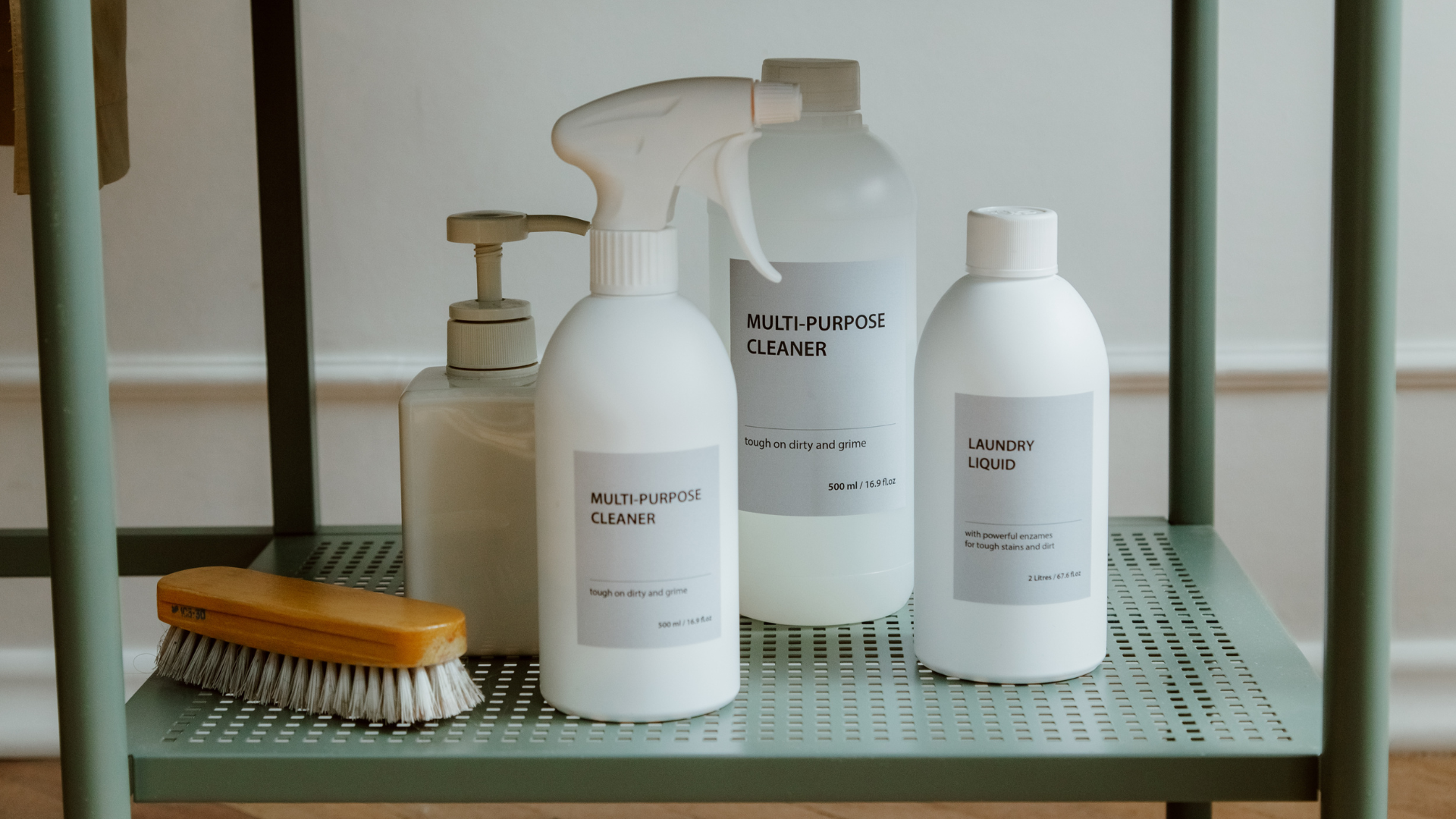 White hair and body care bottles on a green shelf with a wooden brush and pump dispensers