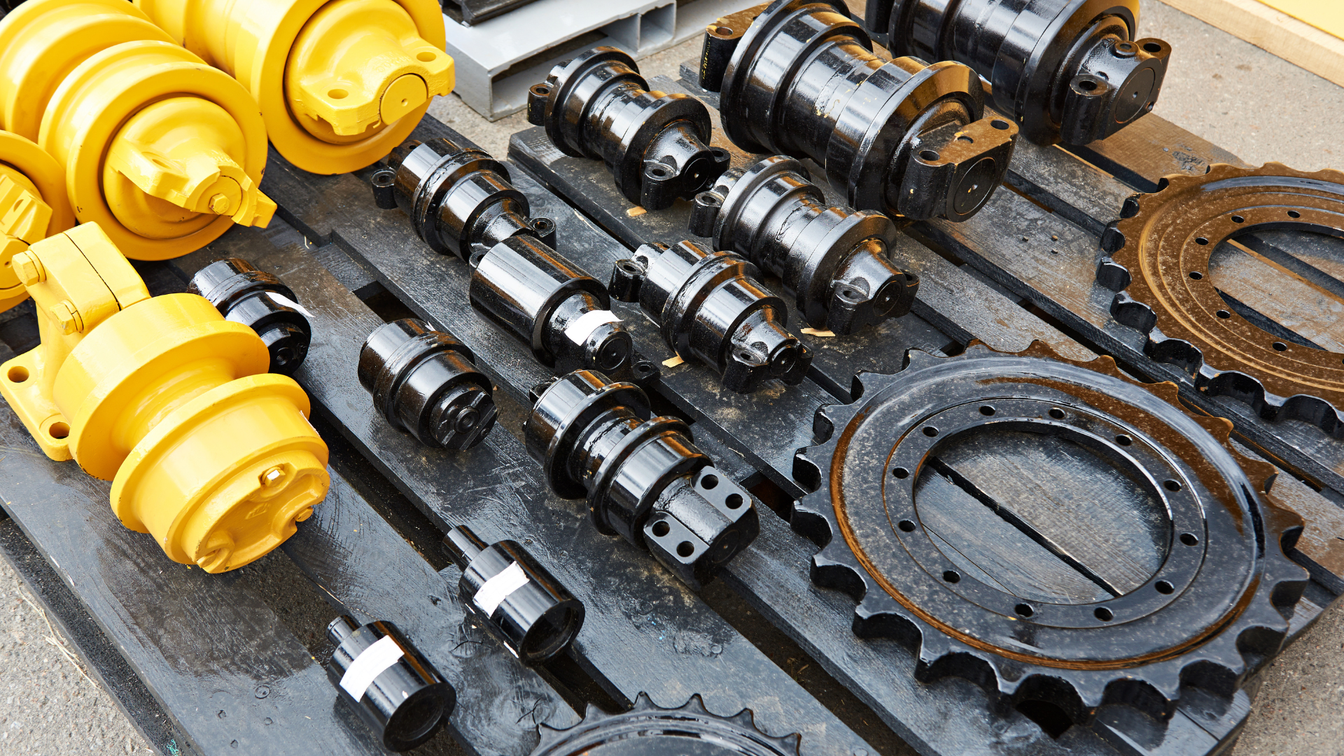 Assorted industrial gears, shafts, and mechanical parts arranged on a work surface, including yellow and black components
