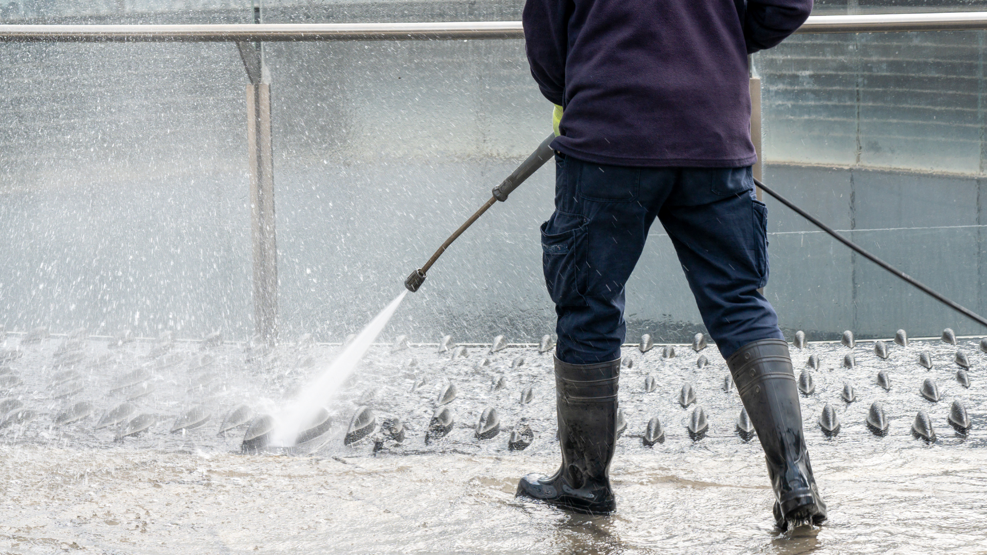 man using excessive water in cleaning an industrial setting
