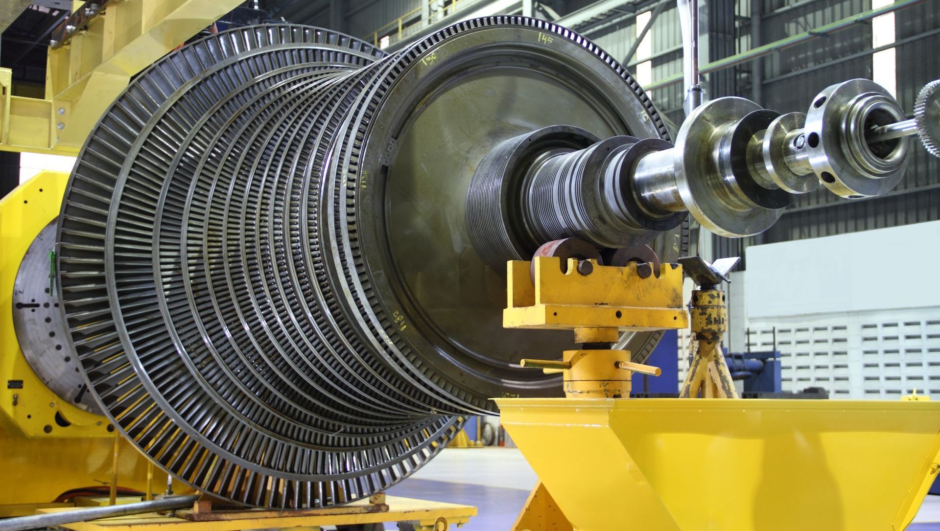 A large turbine is sitting on top of a yellow cart in a factory.