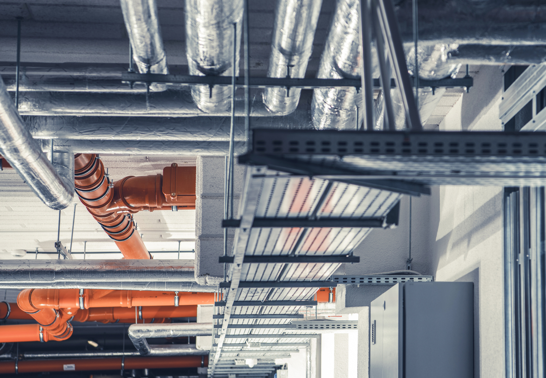 A bunch of pipes are hanging from the ceiling of a building.