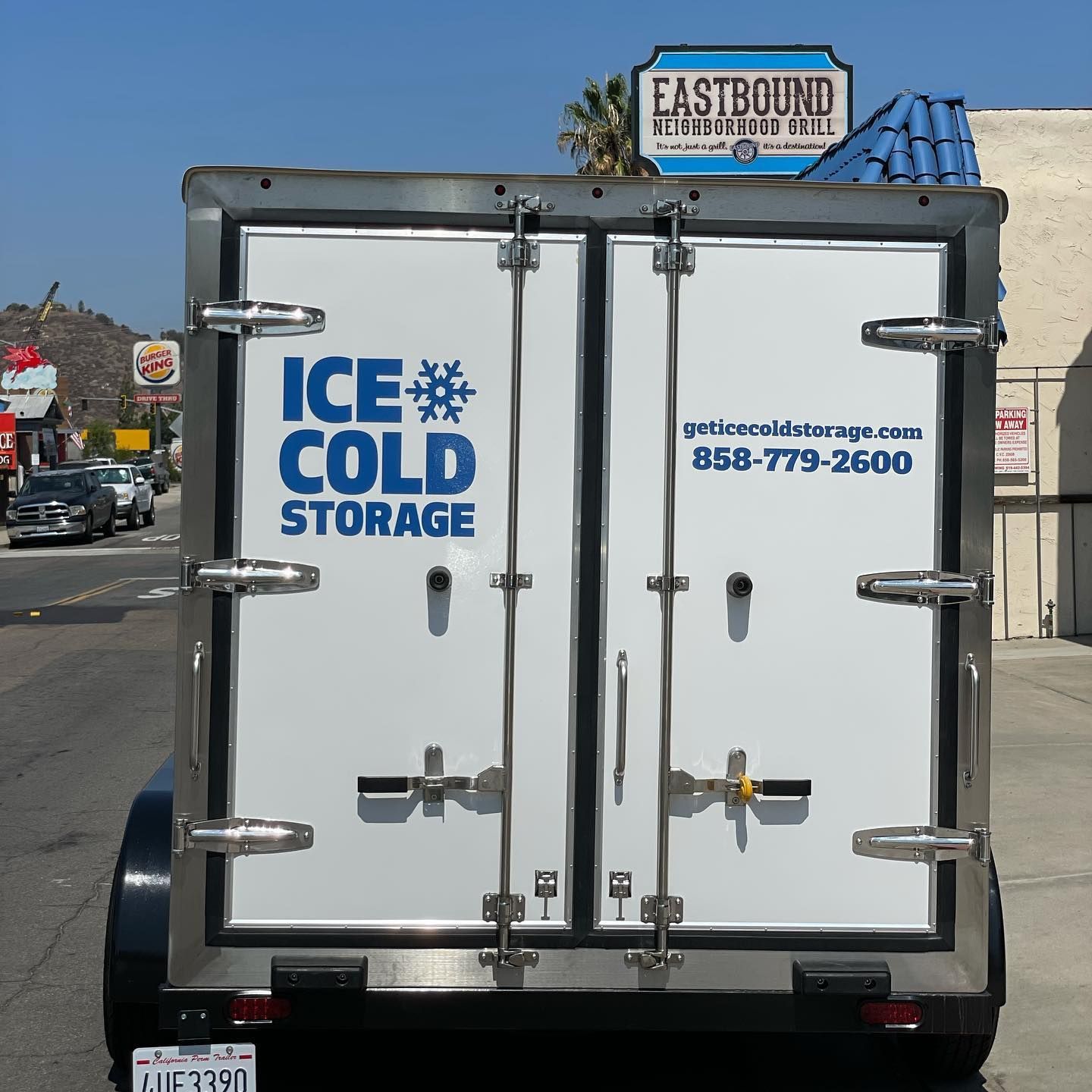 An ice cold storage trailer is parked on the side of the road