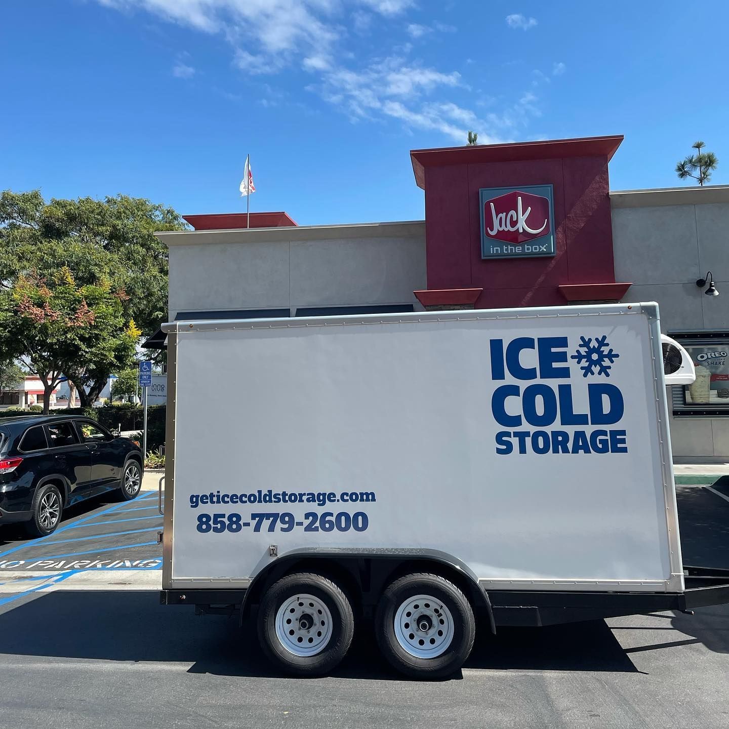 An ice cold storage trailer is parked in front of a jack in the box