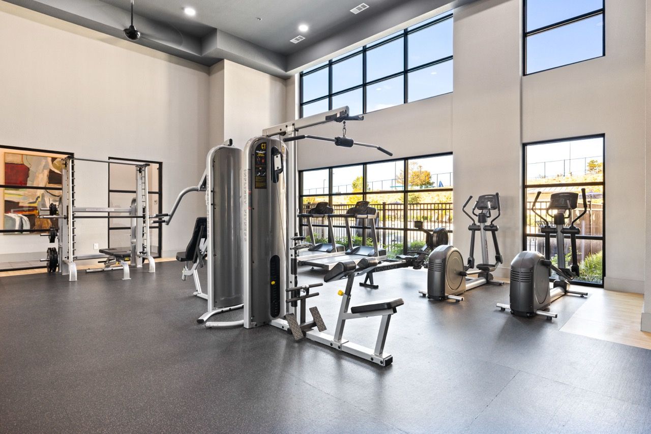Bright modern gym in a multifamily property with cardio machines and weight stations at Olympus Hudson Oaks.
