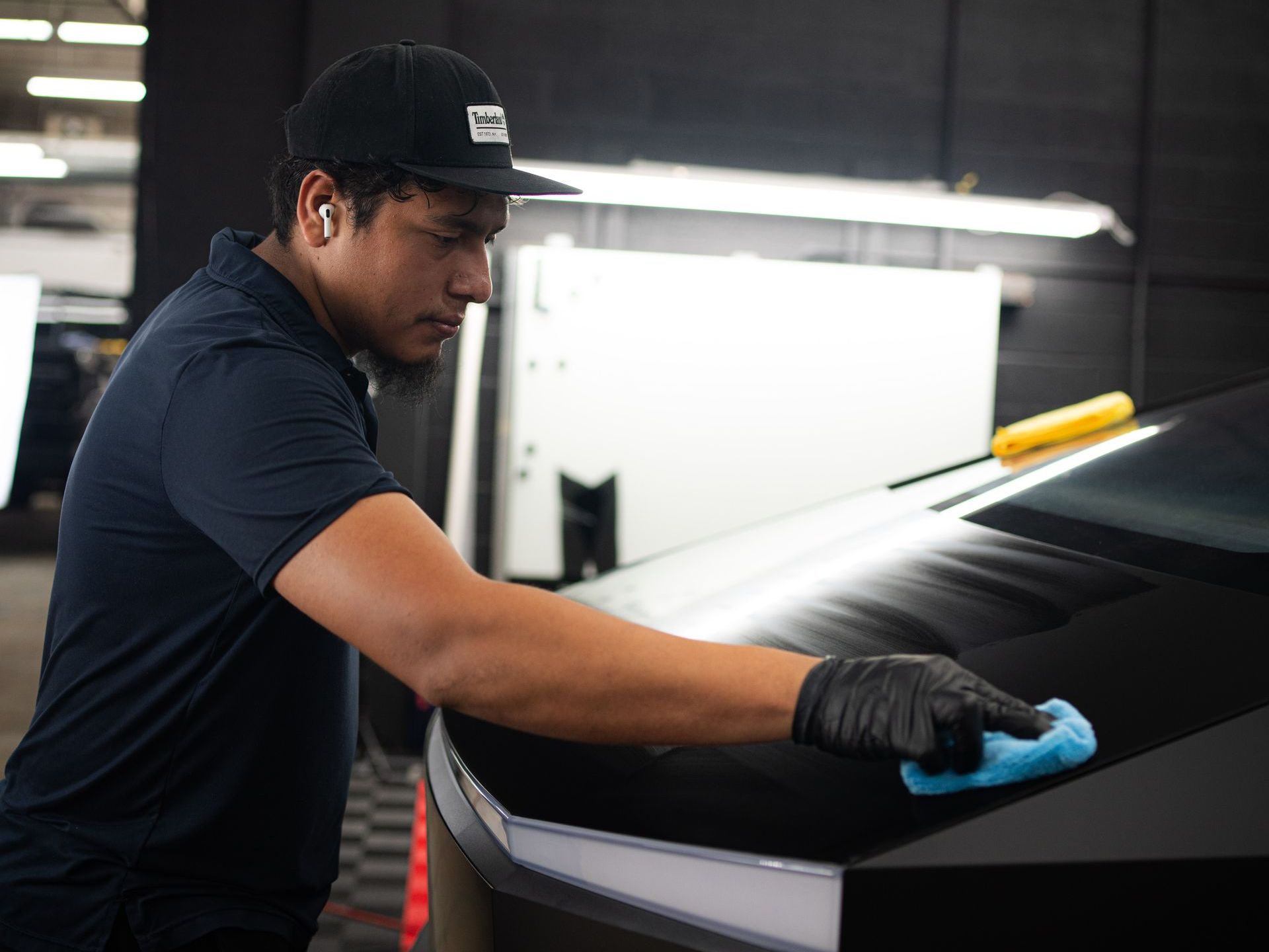 A man is cleaning a car with a cloth in a garage.
