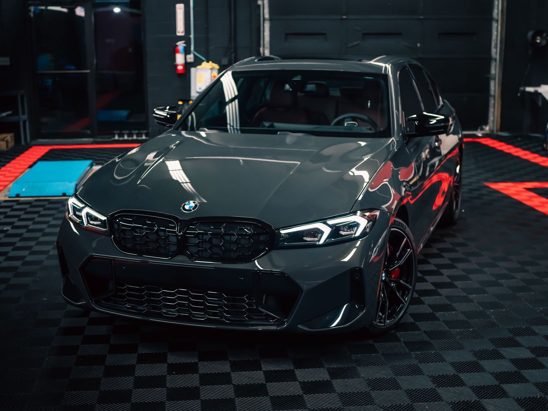 A bmw m3 is parked in a garage on a checkered floor.