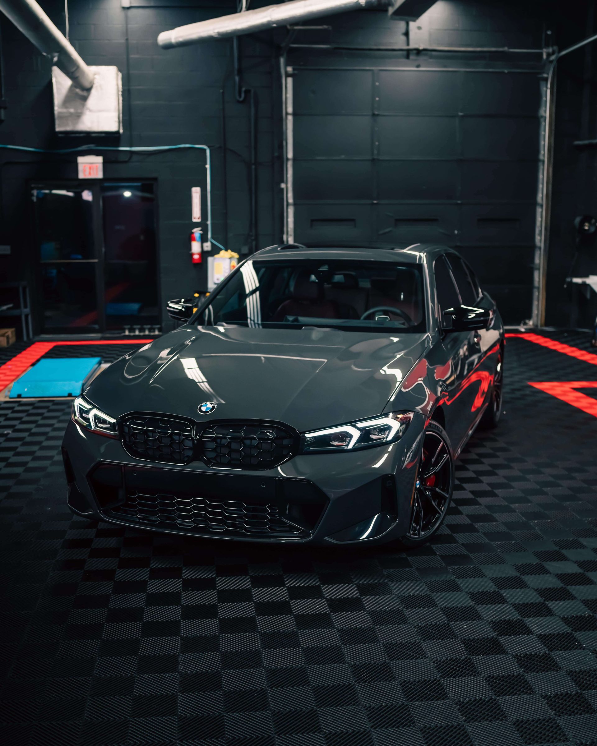 A bmw m3 is parked in a garage with a checkered floor.