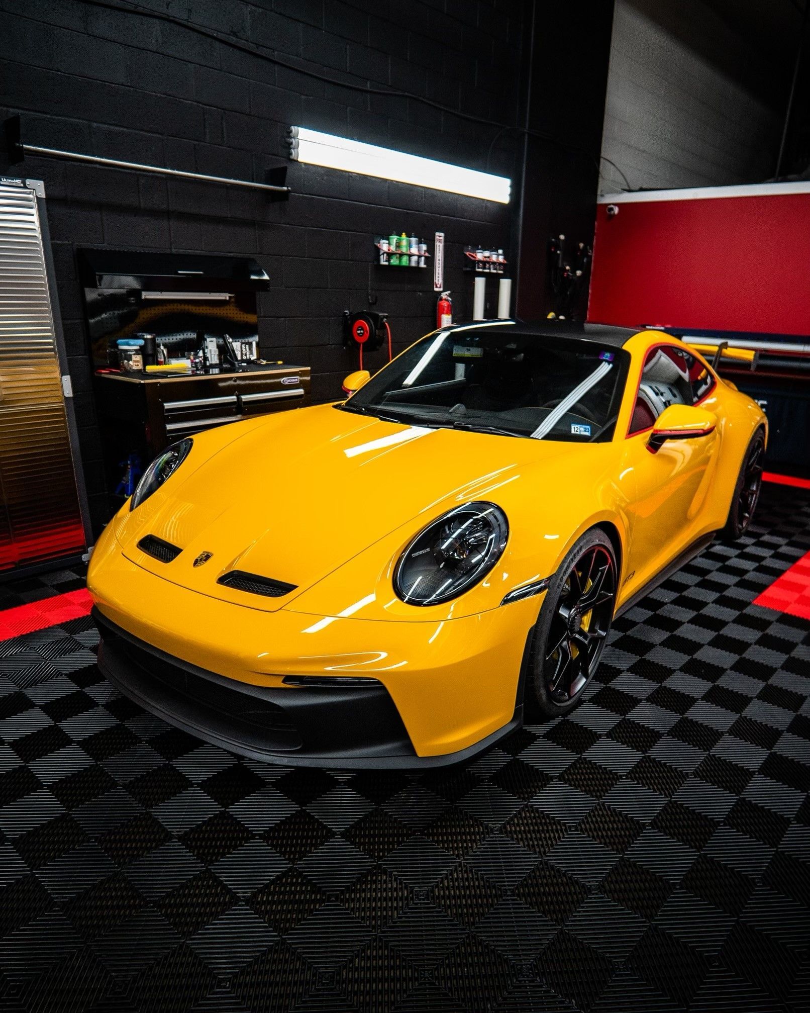 A yellow porsche 911 gt3 rs is parked in a garage.