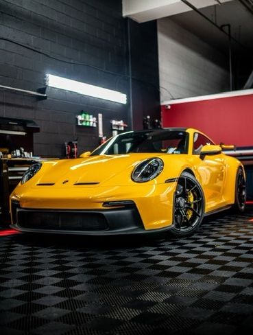 A yellow porsche 911 gt3 is parked in a garage.