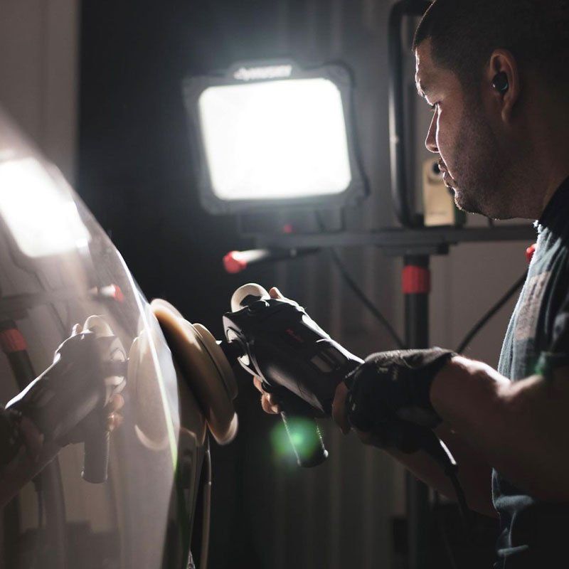 A man is polishing a car in a dark room