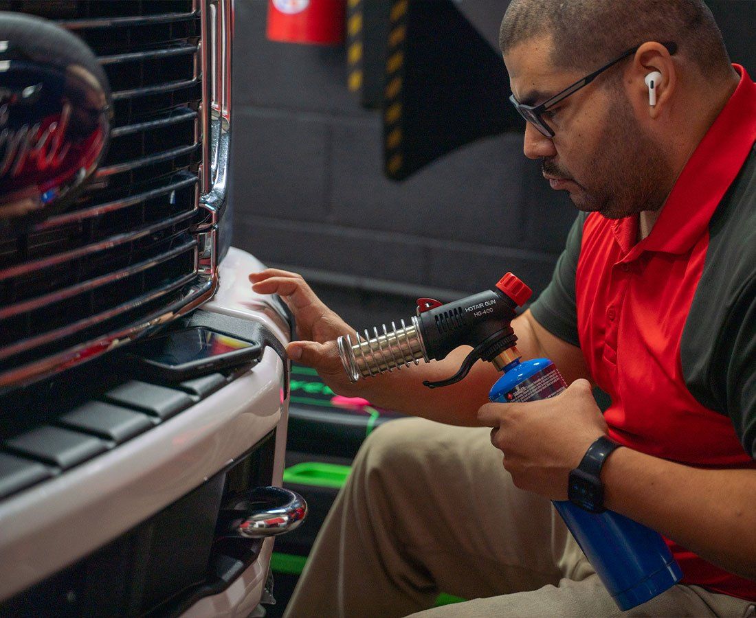 A man is working on the front of a ford truck