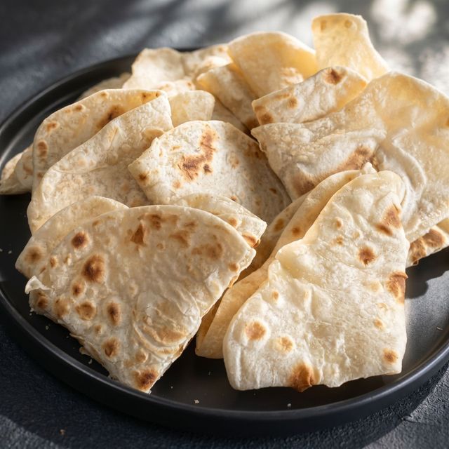 Plate of folded flatbread pieces with light brown spots on a dark plate