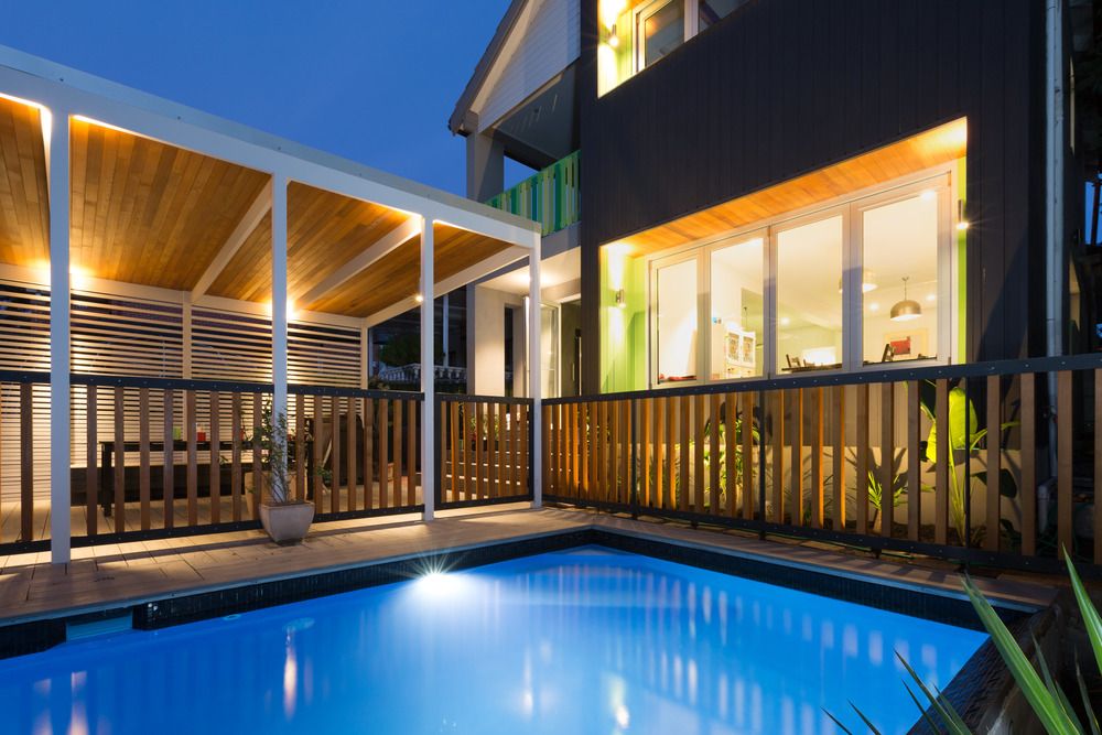 A swimming pool with a deck and house in the background— Superior Windows & Doors Taree, NSW