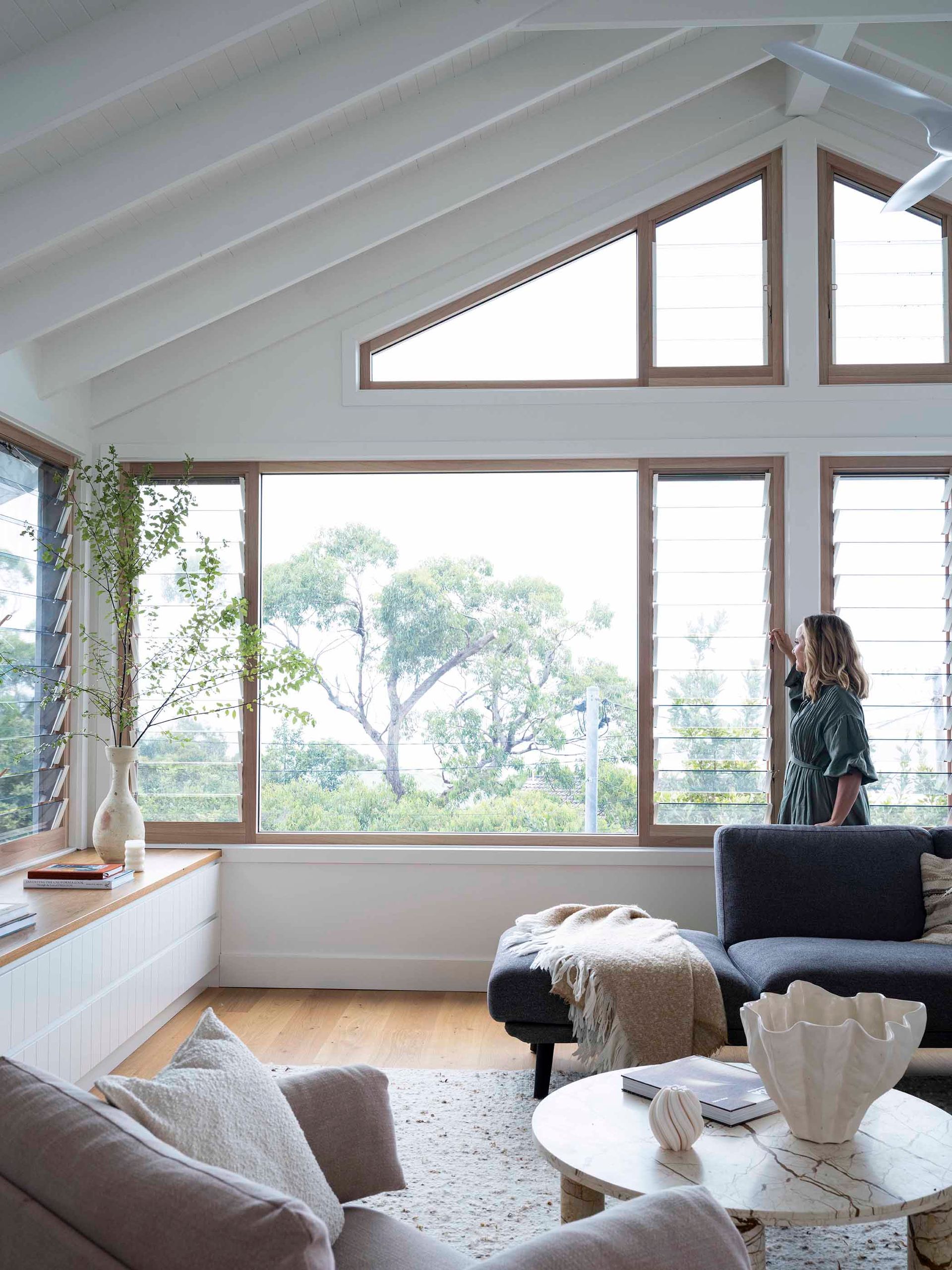A women in her living room closing some Louvre windows   — Superior Windows & Doors Taree, NSW
