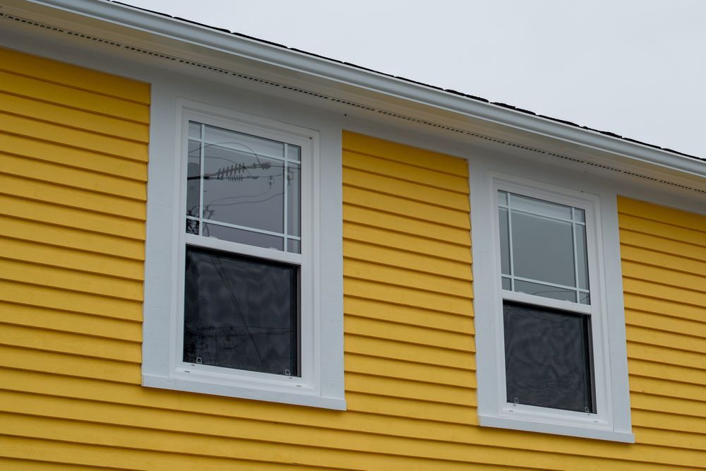 A Yellow House With White Trim and Two Windows — Superior Windows & Doors Taree, NSW