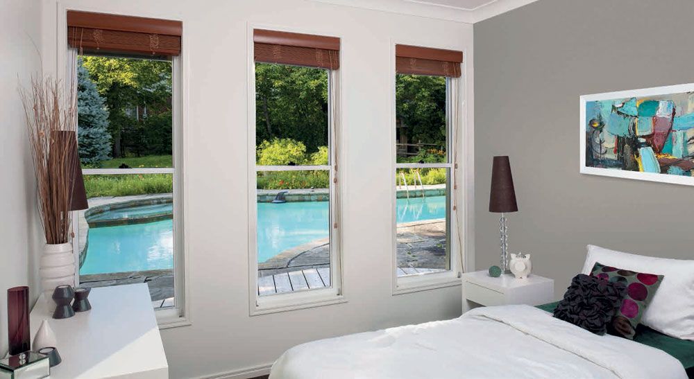 A bedroom with a bed , two windows and a painting on the wall — Superior Windows & Doors Taree, NSW