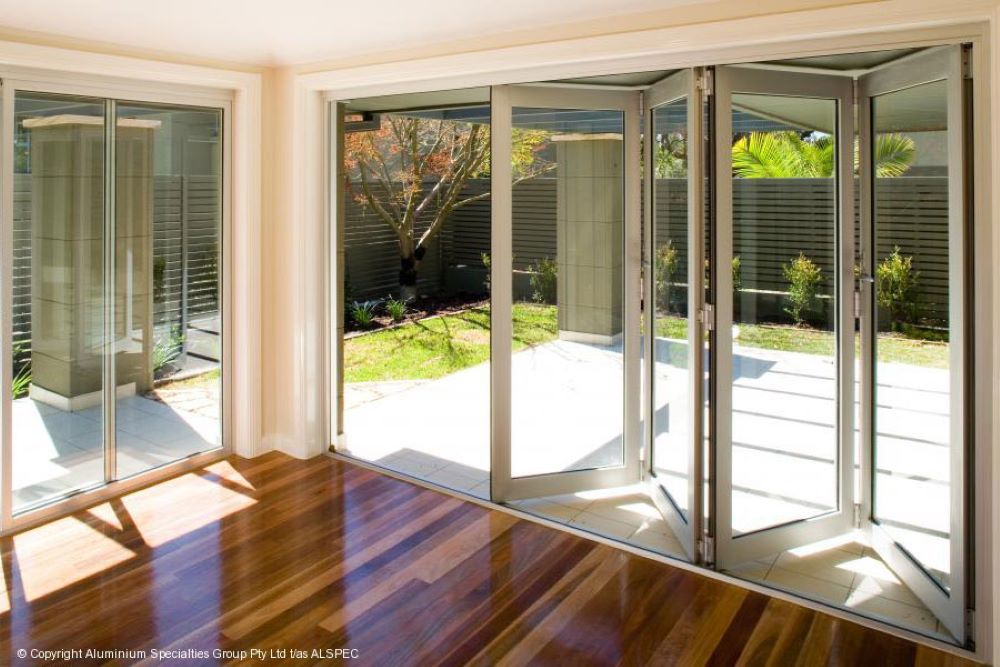 An Empty Room With Sliding Glass Doors Leading to a Patio — Superior Windows & Doors Taree, NSW