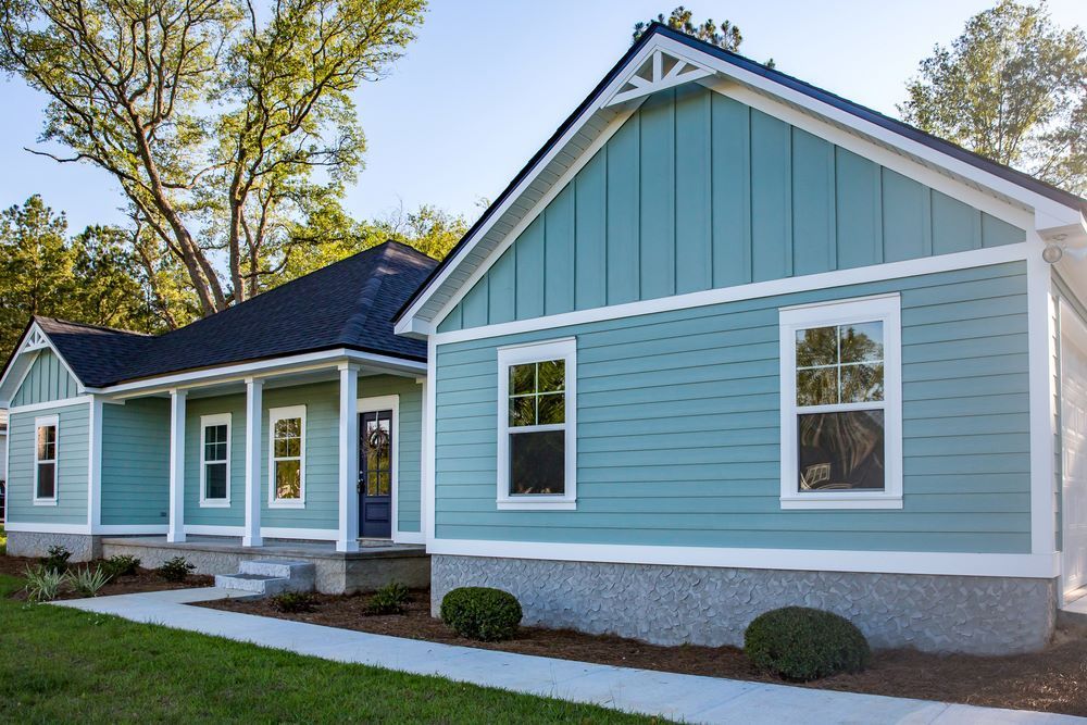 A Blue House With White Trim and a Black Roof — Superior Windows & Doors Taree, NSW
