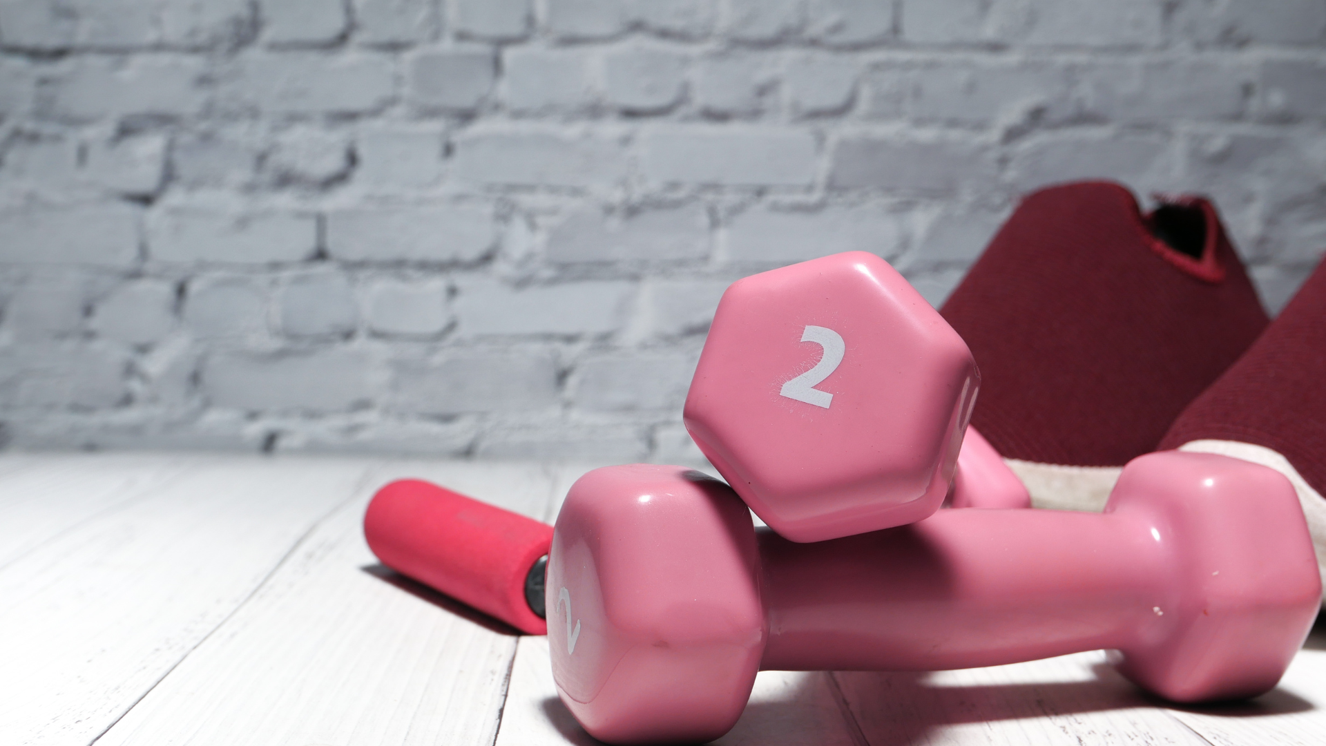 A pair of pink dumbbells sitting on top of a wooden table.