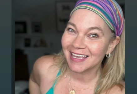 A woman wearing a headband and a necklace is smiling.