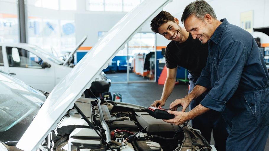 Two mechanics inspect a car engine in a bright auto repair shop