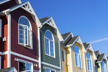 Row of colorful townhouse facades with gabled roofs against a blue sky