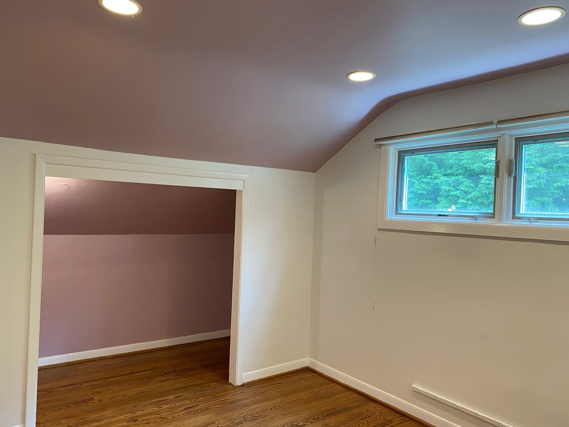 An empty room with a pink ceiling and a window.