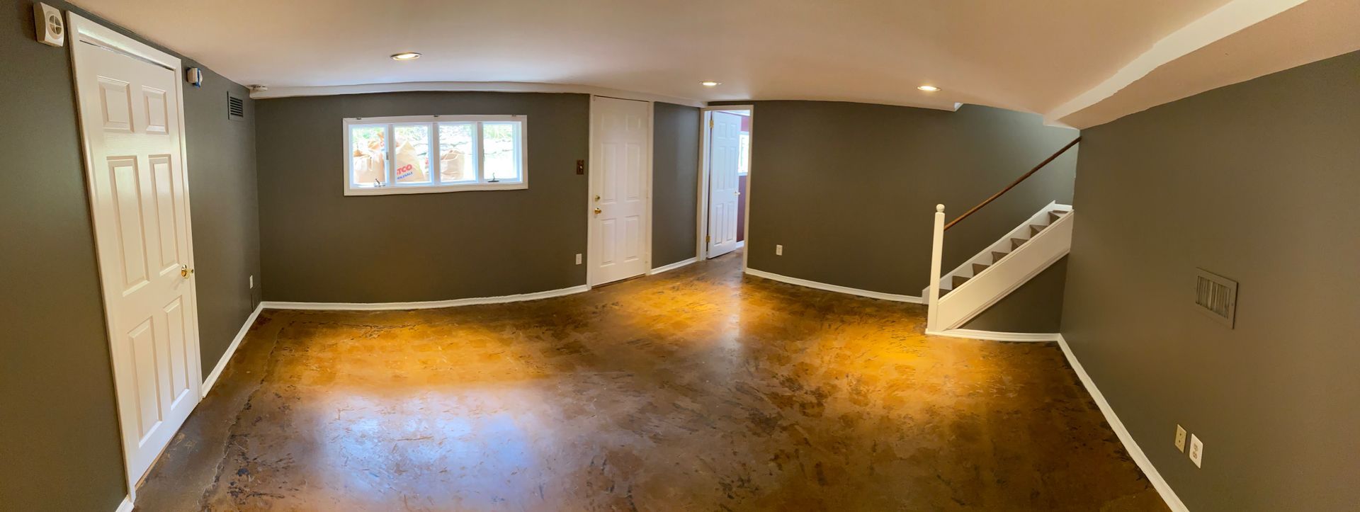 An empty basement with hardwood floors and stairs.
