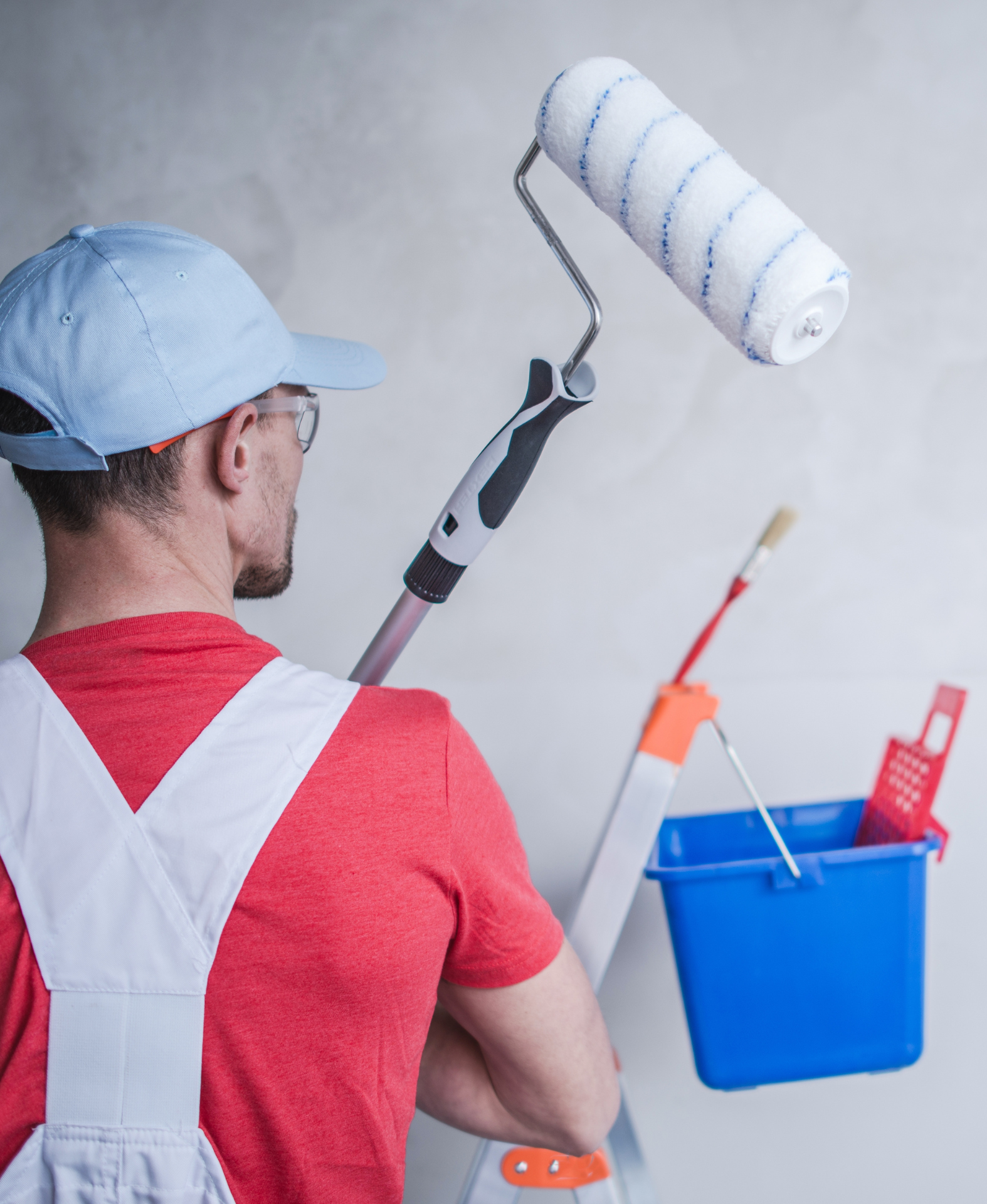 A man is painting a wall with a paint roller.