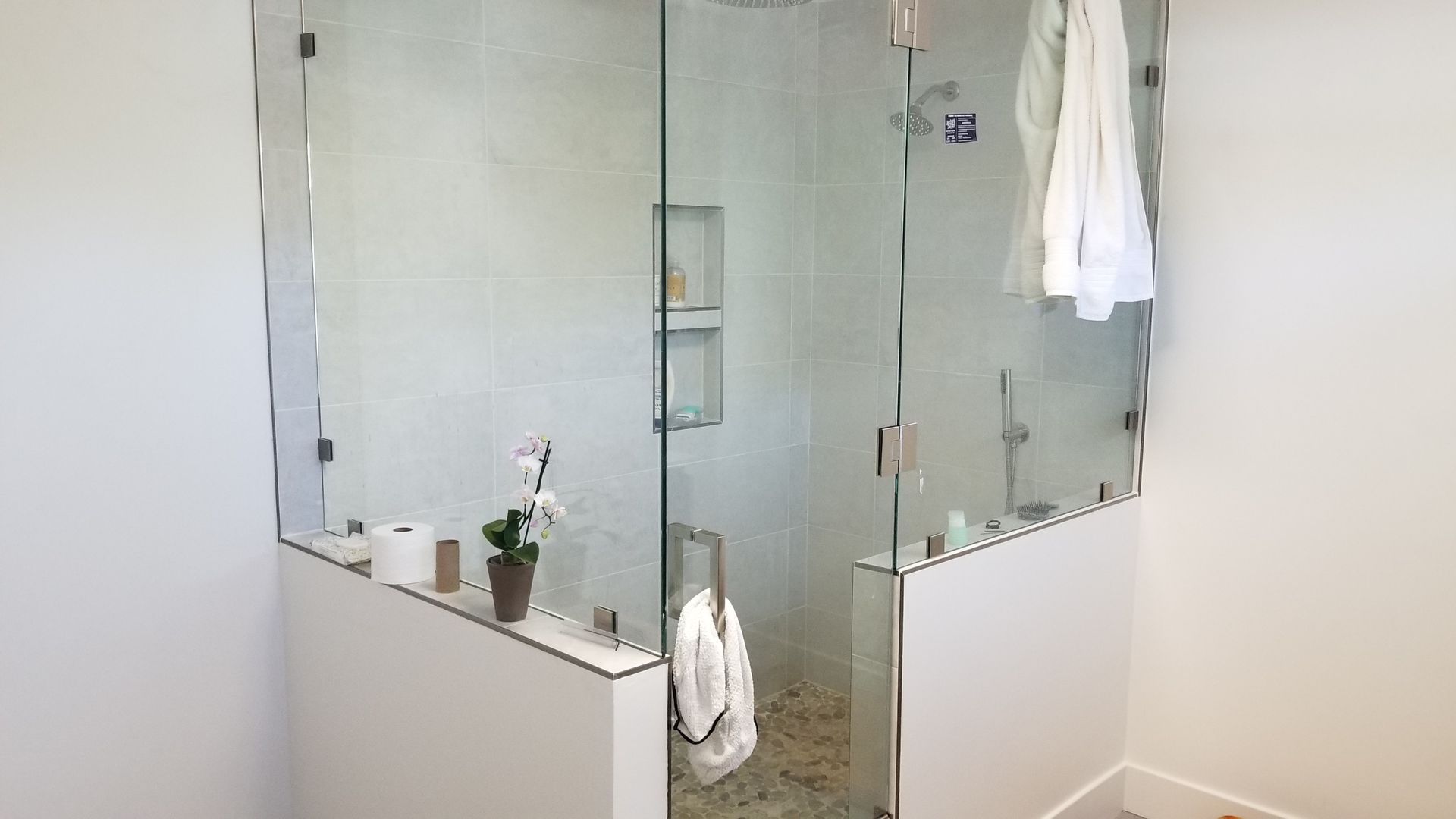 A bathroom with a walk in shower with a glass door.