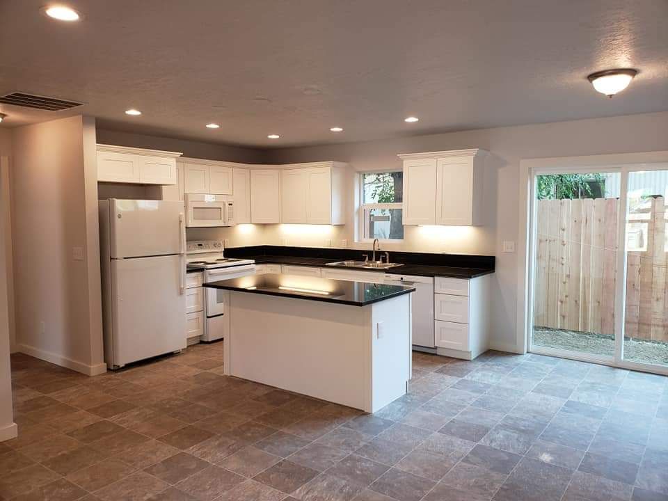 An empty kitchen with white cabinets and black counter tops