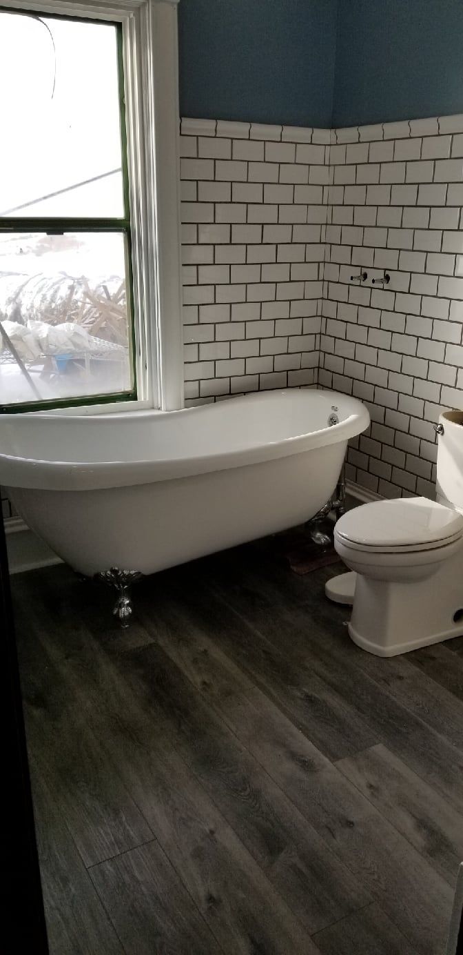 A bathroom with a tub , toilet and window.