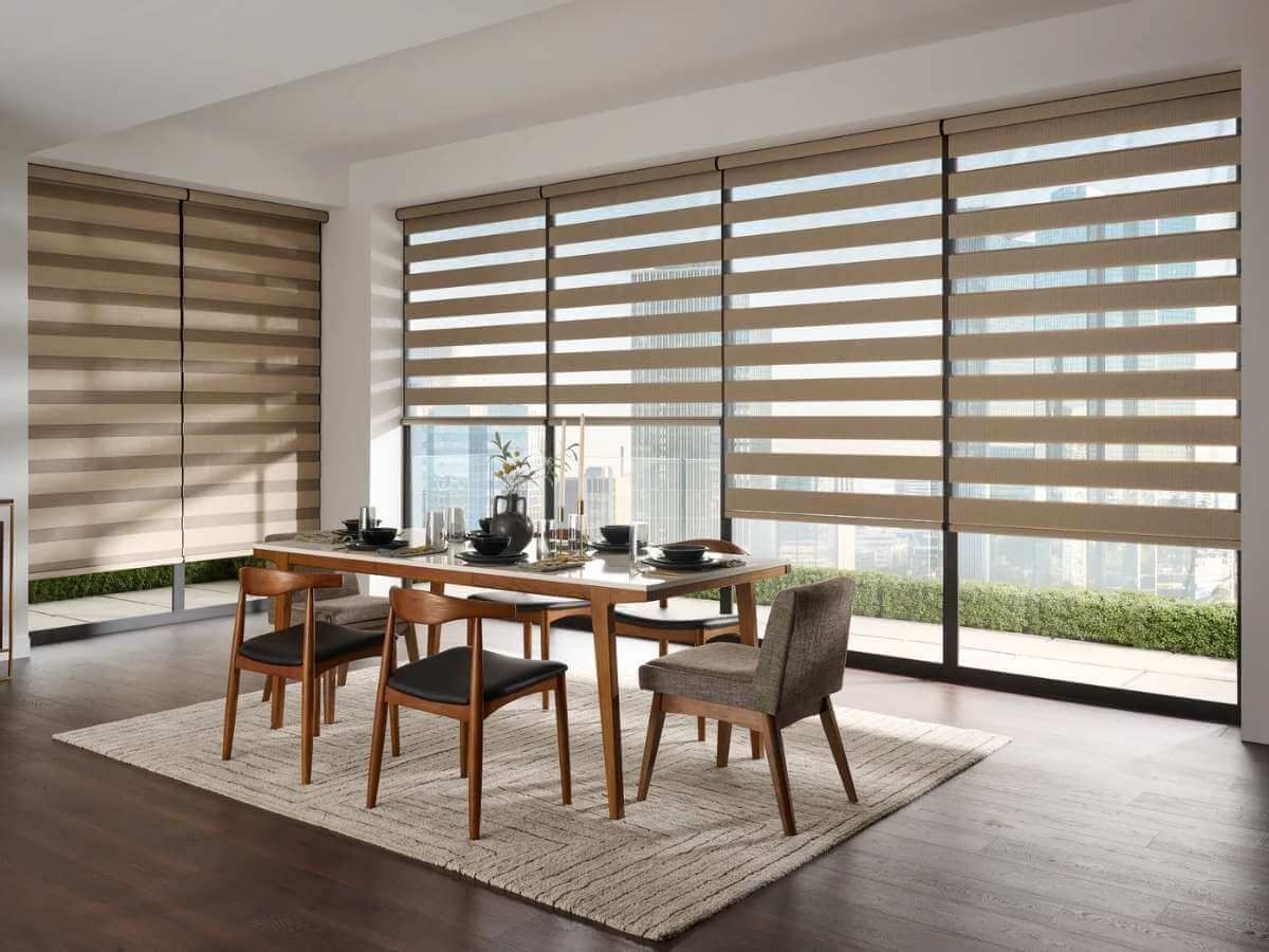 Dining room with a table, chairs, and large window with layered blinds.