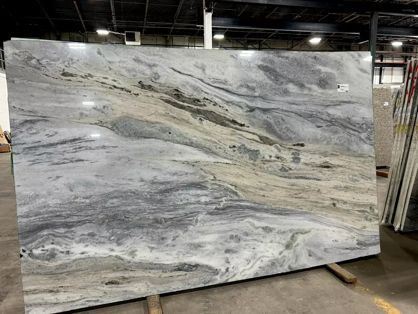 A large slab of marble is sitting on top of a wooden pallet in a warehouse.