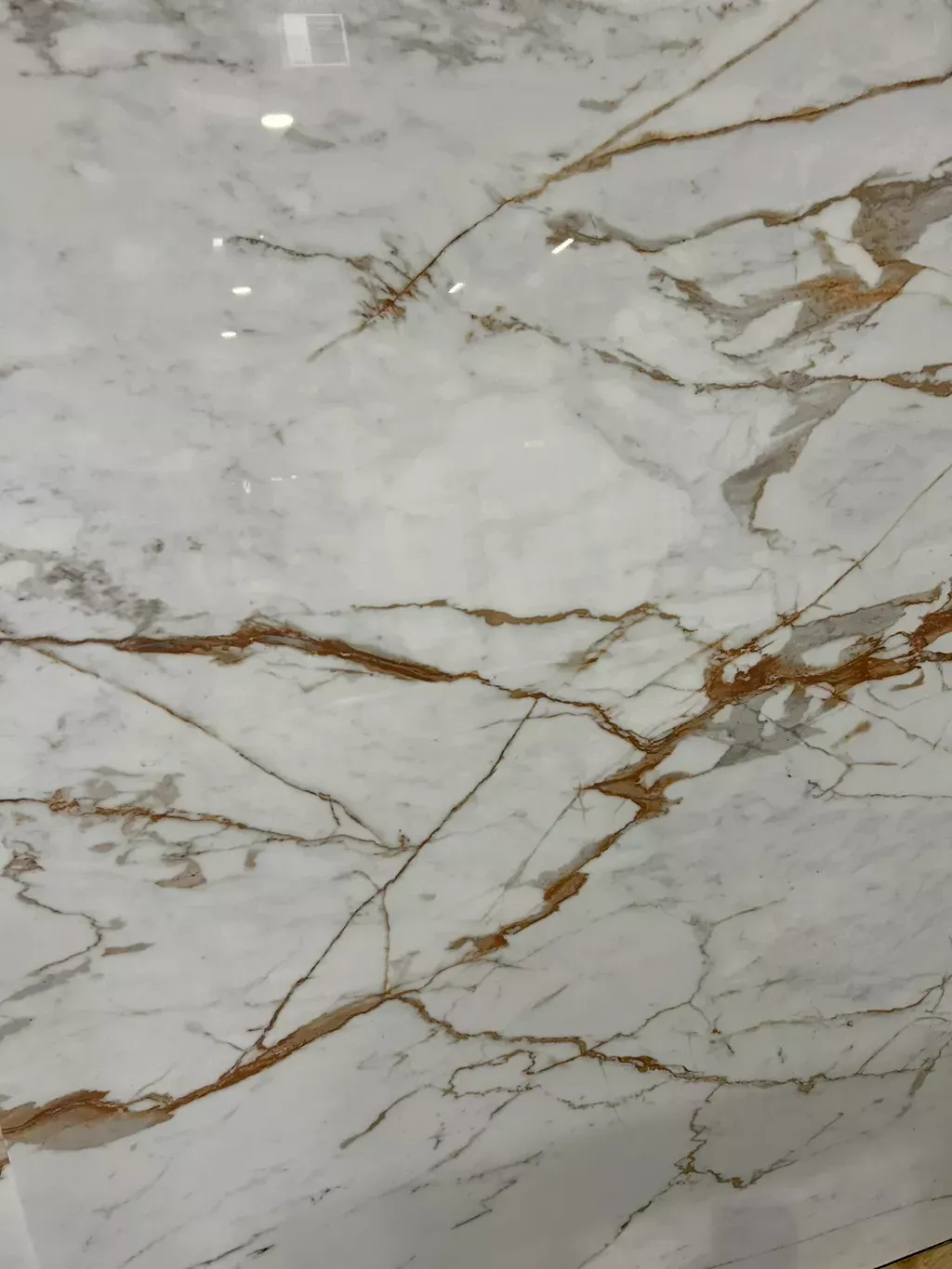 A close up of a white marble tile with brown veins