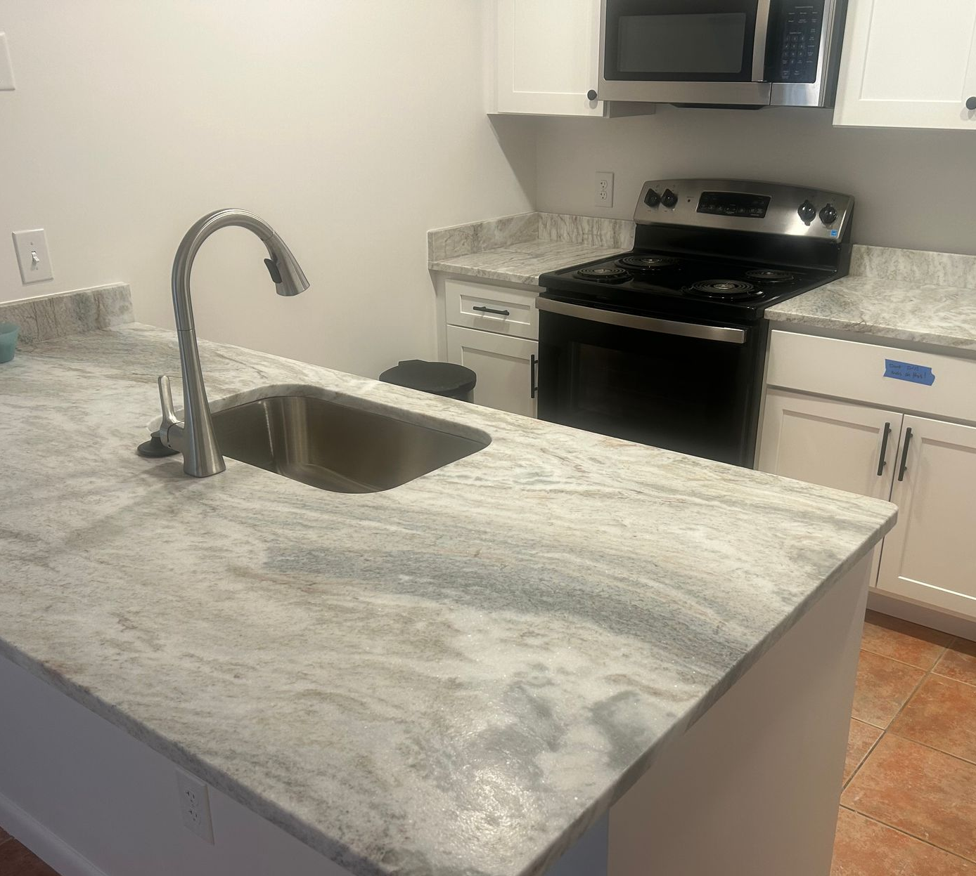 A kitchen with a large white counter top and a sink.