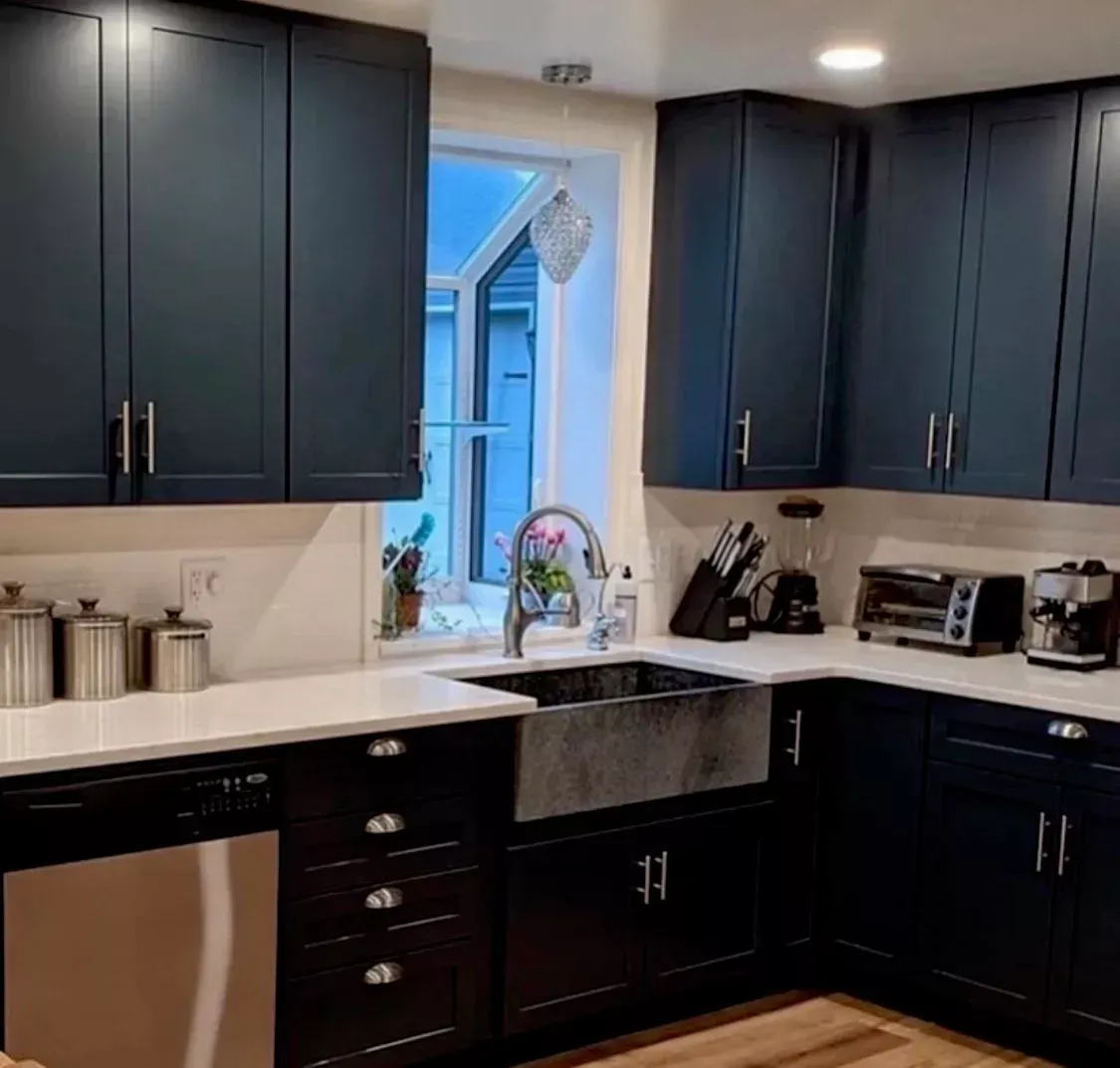 A kitchen with black cabinets , a sink , and a window.