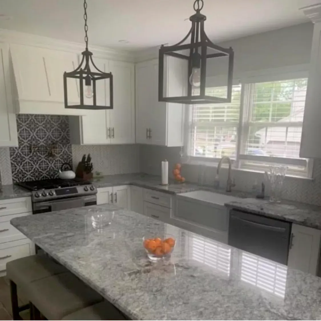 A kitchen with white cabinets , granite counter tops , a sink and a stove.