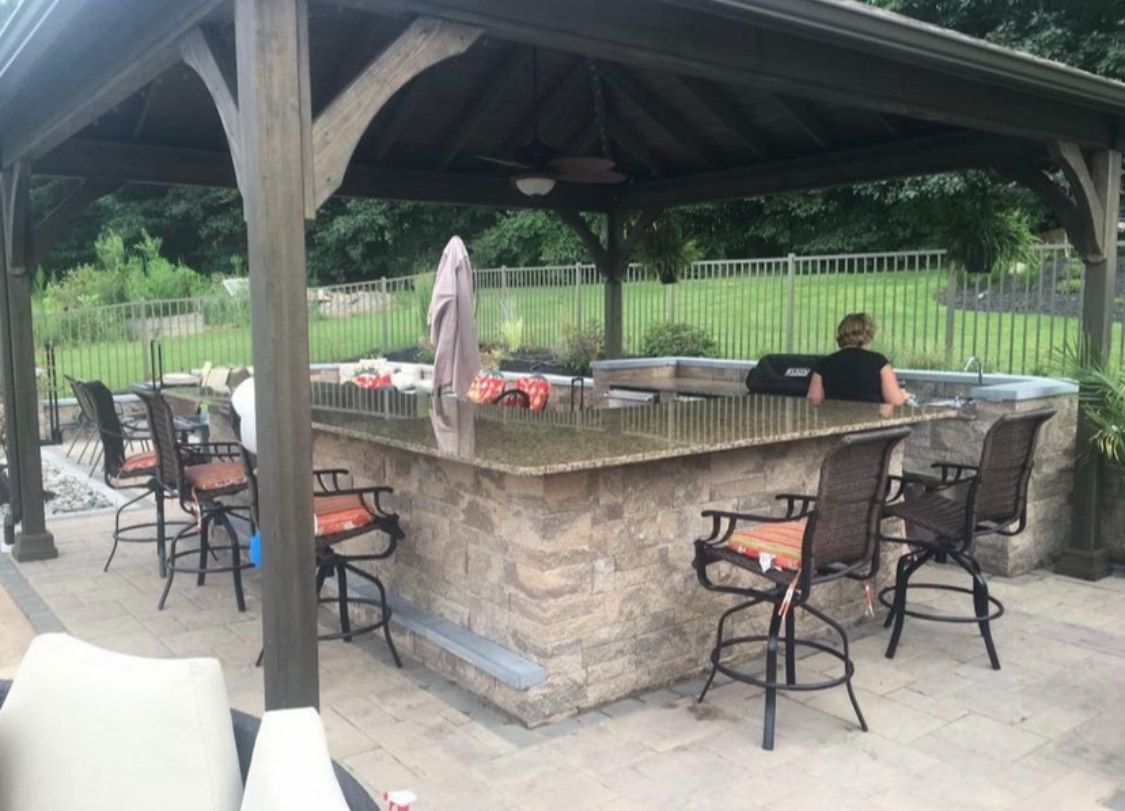 A woman is sitting at a bar under a gazebo.