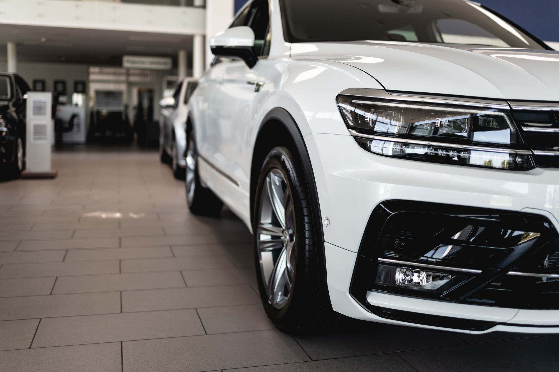 White SUV displayed indoors at a car dealership, front view on showroom floor | Cruz-N-Carz