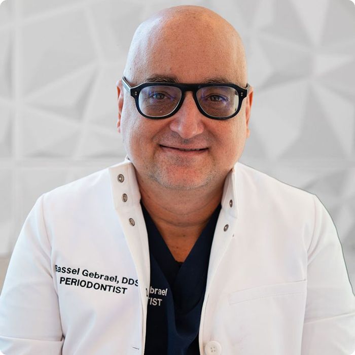 Smiling dentist wearing glasses and a lab coat.