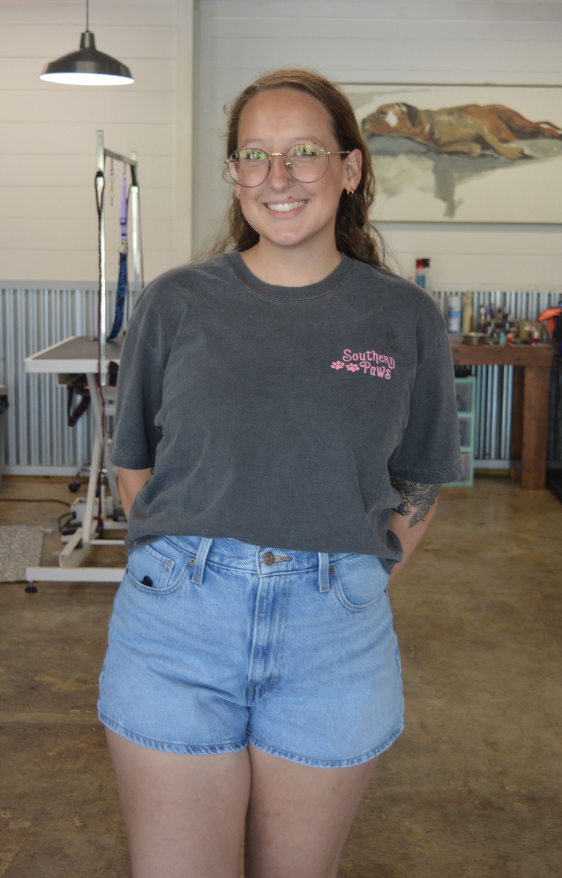 A woman in a green t-shirt and blue jeans is standing in a room.