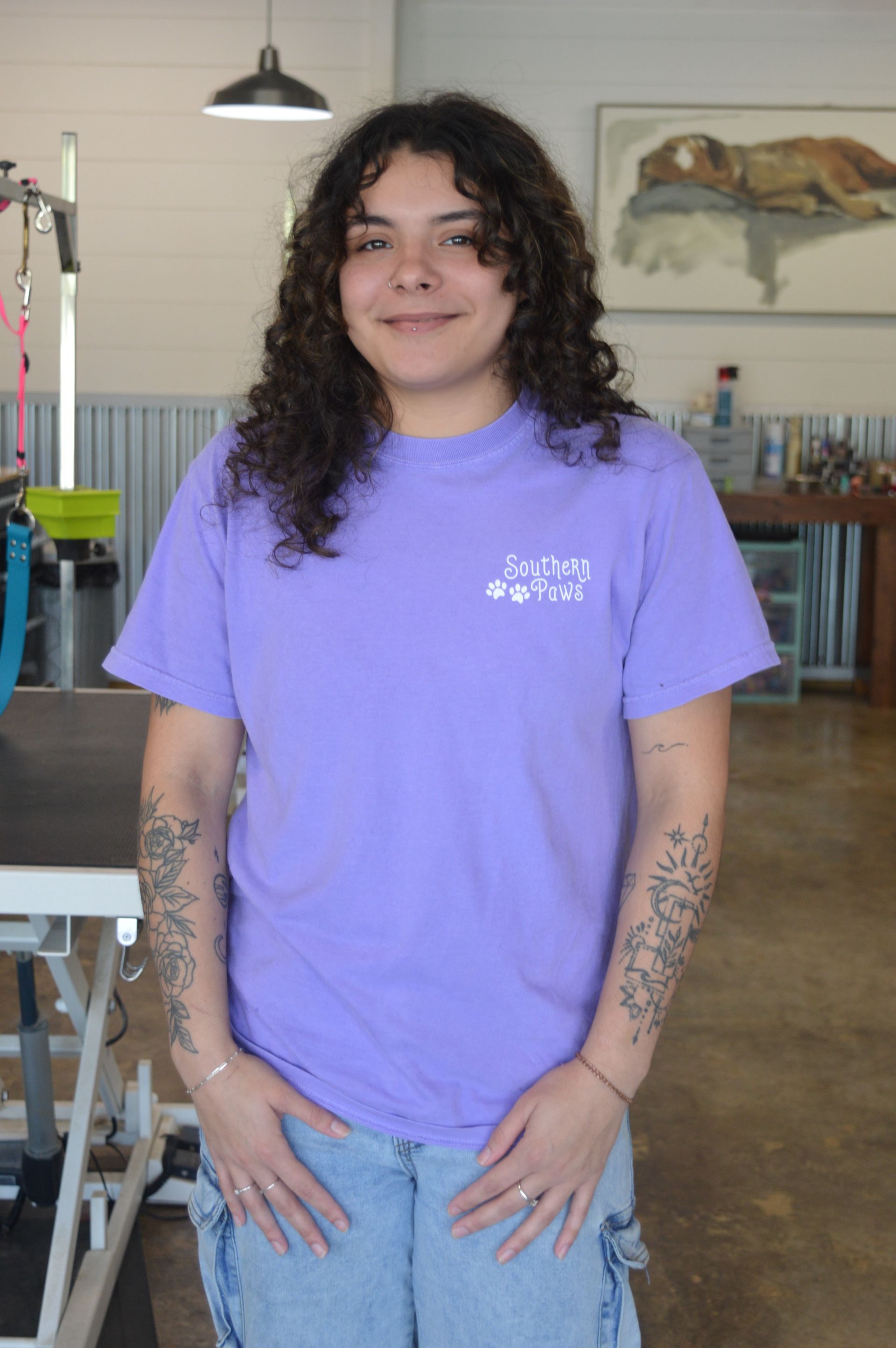 A young woman with long hair is wearing a green t-shirt and jeans.