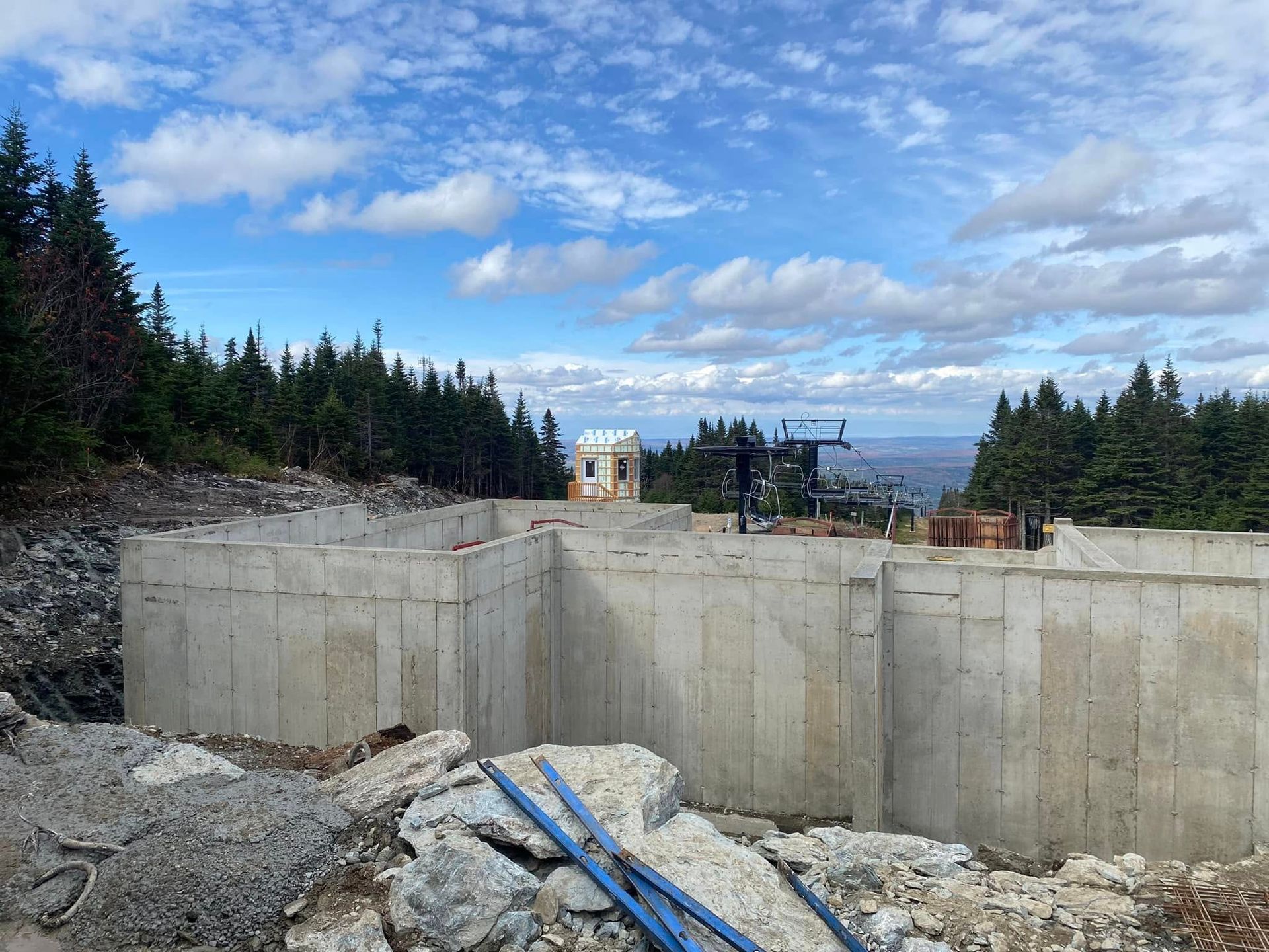 Un grand mur de béton est en train d'être construit au milieu d'une forêt.