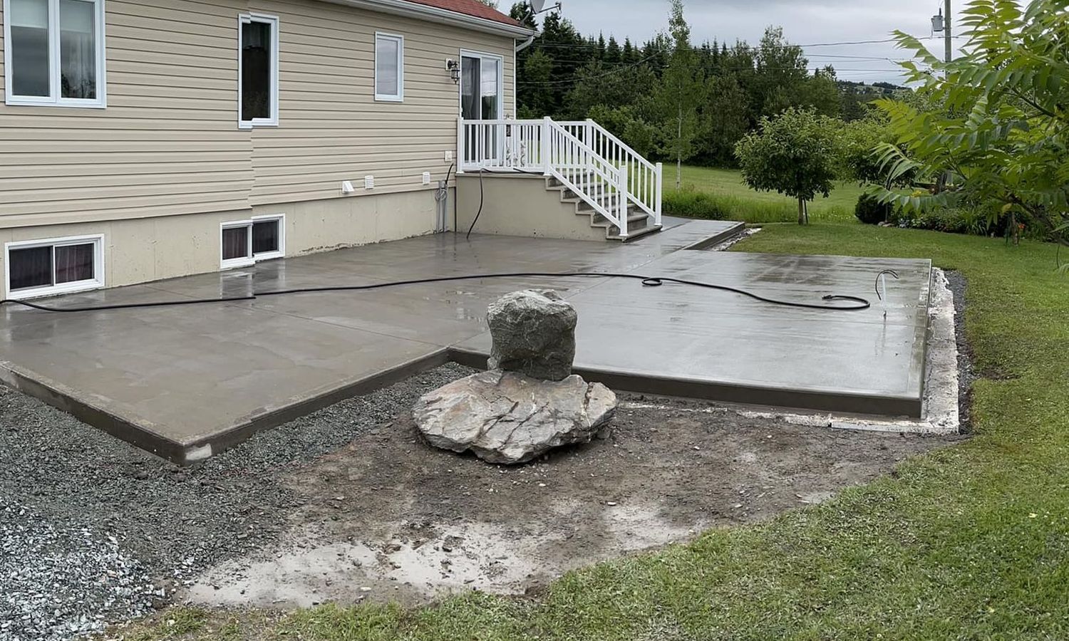 Un patio en béton est en cours de construction devant une maison.