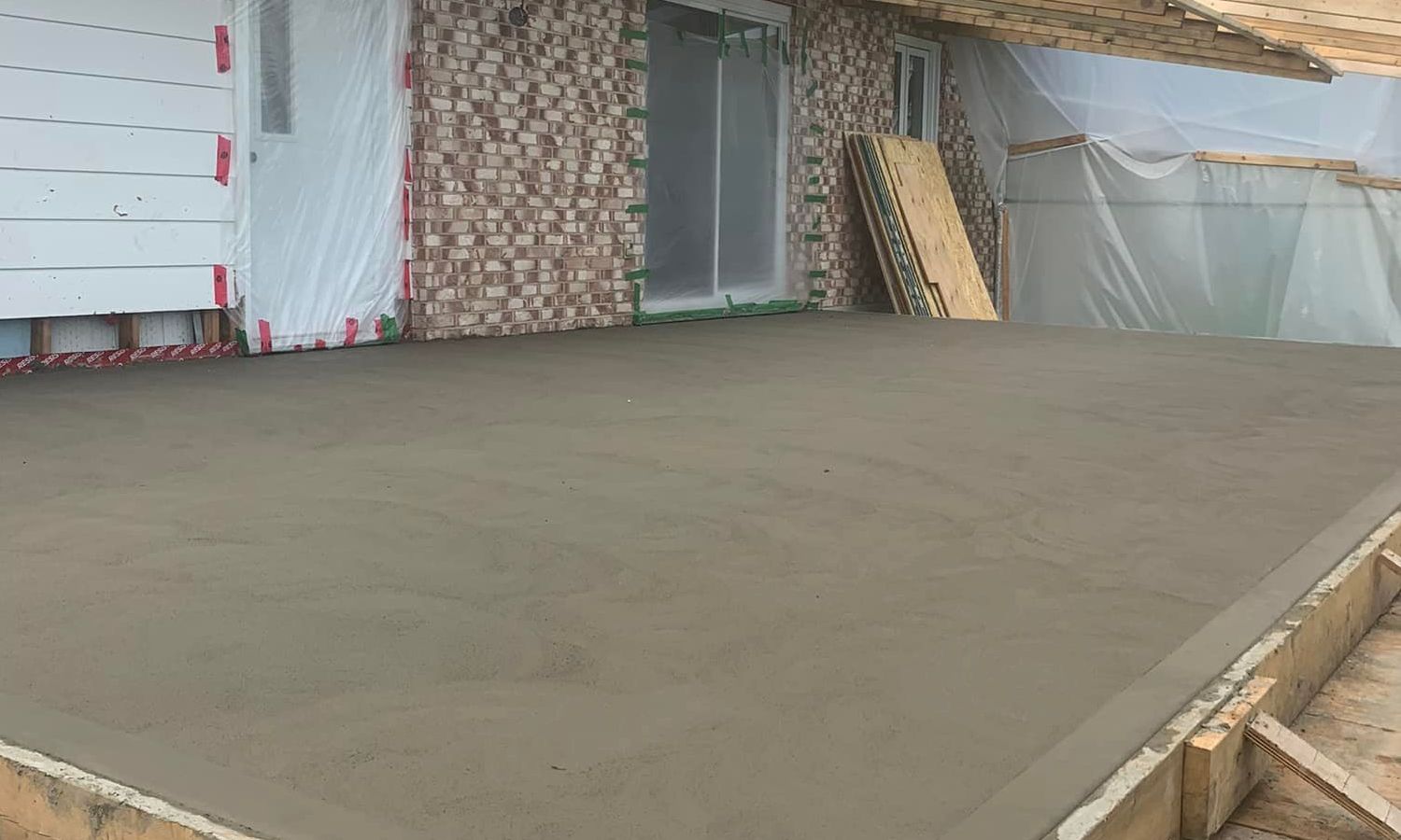 Un patio en béton est en cours de construction devant une maison.