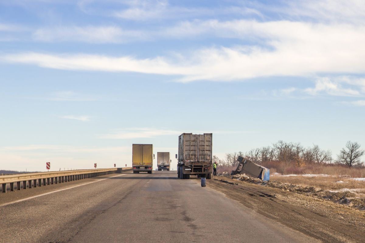 A row of semi trucks are driving down a highway.